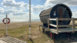 Una cabana de fusta amb una porta, un flotador i un remolc amb rodes vermelles.