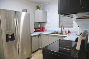 Una cocina moderna con electrodomésticos de acero inoxidable, dispensador de agua, microondas y pileta.
