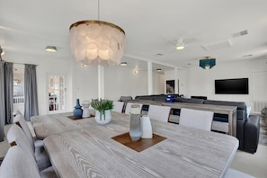 A spacious living area with a large wooden dining table, a modern chandelier, and a comfortable seating arrangement. - Fire & Oaks Estate (Tybee Island)