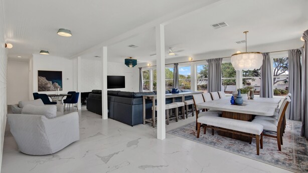A spacious living area with a dining table, a sofa, and a kitchen area. - Fire & Oaks Estate (Tybee Island)