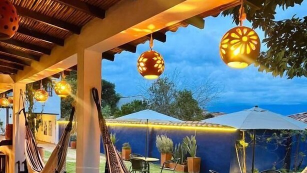 A covered outdoor area with hammocks, tables, chairs, and potted plants. - Pancha Mama Hotel Boutique (Villa de Leyva)