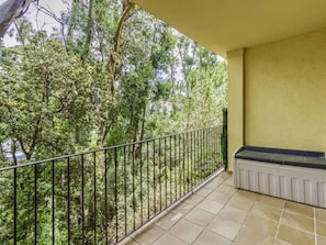 Ein Balkon mit Metallgeländer, einem weißen Heizkörper und Blick auf dichtes Grün.