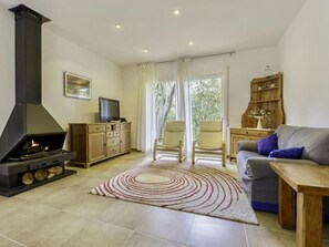 Ein Wohnzimmer mit Kamin, einer Couch, einem Fernseher und einem Holzschrank.