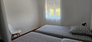 A room with two beds, a white chair, a lamp, and a window with blinds. - The renovated village house “Adèlbraz”   (Voulaines-les-Templiers)