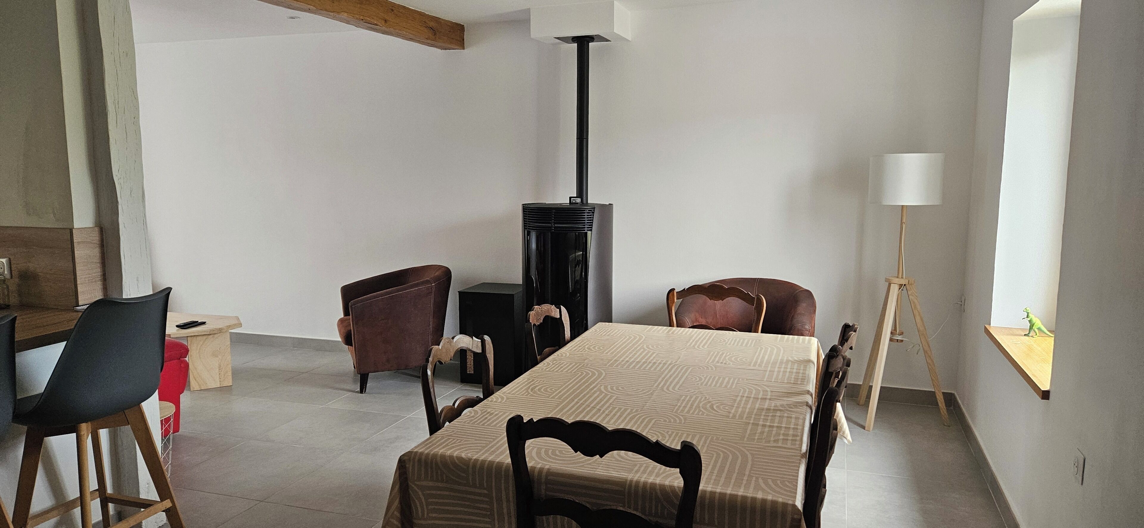Een eetgedeelte met een tafel, stoelen, een elektrische kachel en een lamp.