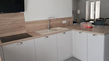 Ett modernt kök med en inbyggd diskho, träinredning och en platt-TV som är monterad ovanför bänkskivan.