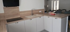 Eine moderne Küche mit integriertem Spülbecken, Holzschränken und einem Flachbildfernseher, der über der Arbeitsplatte angebracht ist.