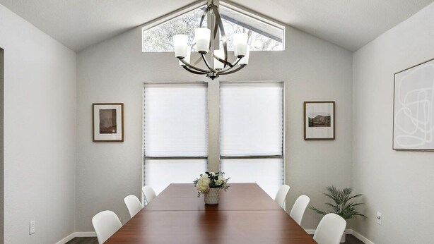 A dining room with a wooden table, white chairs, a chandelier, and framed pictures on the walls. - Candleridge Casa - Newly Remodeled 4-bd Hidden Gem (Fort Worth)