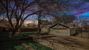 A residential property with a garage, a driveway, and a large tree. - Candleridge Casa - Newly Remodeled 4-bd Hidden Gem (Fort Worth)