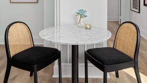 En matplats med ett runt bord, två svarta stolar, en vit avskärmning och ett inramat citat på väggen.