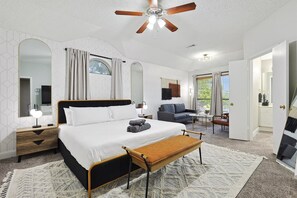 A bedroom with a bed, bedside tables, a bench, a ceiling fan, and a view of the outside. - Modern Comforts & Classic Charm w Pool, 5BD (Fort Worth)