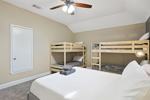 A bedroom with two bunk beds, a ceiling fan, a door, and a bedside lamp. - Modern Comforts & Classic Charm w Pool, 5BD (Fort Worth)