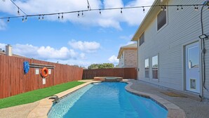 En trädgård med en pool, ett trästaket och ett hus.