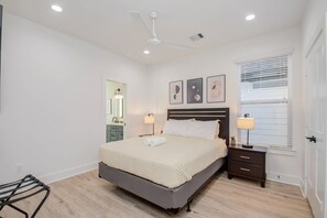 A bedroom with a bed, bedside tables, a ceiling fan, a window with blinds, and a mirror. - Modern Farmhouse, Mins Restaurants & Attractions (Houston)