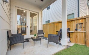 A patio with wicker furniture, a grill, and a wooden fence. - Modern Farmhouse, Mins Restaurants & Attractions (Houston)