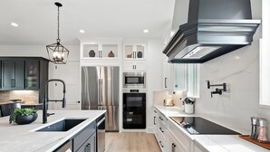 A modern kitchen with stainless steel appliances, white cabinetry, and a black range hood. - Heavenly Retreat 5bd/5.5ba of Waterfront living (Gainesville)