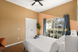 A bedroom with a bed, a white door, a window with curtains, a plant, and a ceiling fan. - Best of Saginaw 4bd/2ba w Pool, Pool Table & BBQ (Fort Worth)