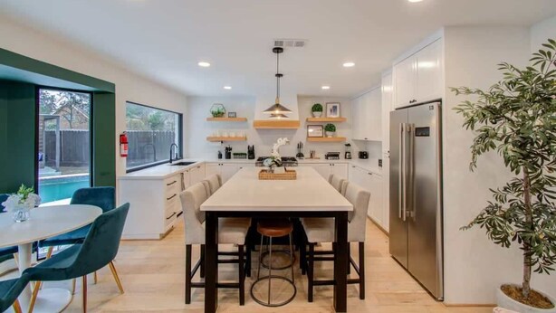 A modern kitchen with a central island, white cabinetry, and a built-in refrigerator. - Spring Branch Paradise, 4-bd Backyard Pool Oasis (Houston)