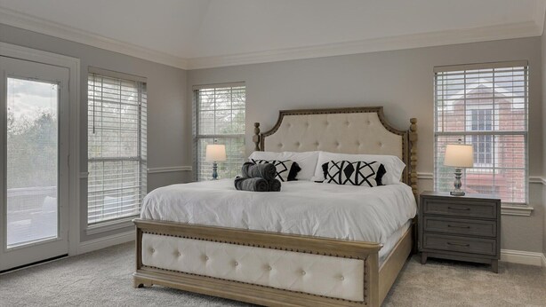 A bedroom with a large bed, two bedside tables, and a window with blinds. - 5BR Oasis w/ Pool Steps From Lake Ray hubbard (Rowlett)