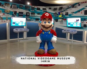 Una estatua de Mario en un museo con pantallas interactivas y un panel de control.