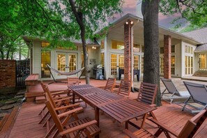 Eine Holzterrasse mit Gartenmöbeln, einer Hängematte und einem Grillbereich.