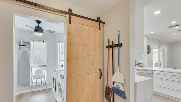 A laundry room with a washing machine, a drying rack, and a broom leaning against the wall. - Perfect Getaway Home w 5 Bedrooms & Backyard Oasis (Plano)