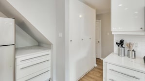 A modern kitchen with white cabinetry, a built-in oven, and a countertop with kitchen utensils. - Perfect Getaway Home w 5 Bedrooms & Backyard Oasis (Plano)