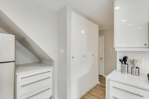 A modern kitchen with white cabinetry, a built-in oven, and a countertop with kitchen utensils. - Perfect Getaway Home w 5 Bedrooms & Backyard Oasis (Plano)