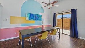 A dining area with a table and chairs, a ceiling fan, and a large window with curtains. - Modern & Chic 4-bd/2-ba Pool, Hot Tub, BBQ Grill (Carrollton)
