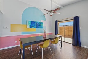 A dining area with a table and chairs, a ceiling fan, and a large window with curtains. - Modern & Chic 4-bd/2-ba Pool, Hot Tub, BBQ Grill (Carrollton)