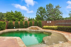 A swimming pool with a stone border, surrounded by a wooden fence and trimmed hedges. - Lewisville Luxe Oasis Pool, Bbq, Theater Room (Lewisville)