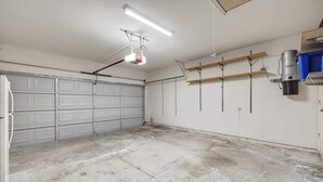 Un garage con pavimento in cemento, porte garage bianche e illuminazione a soffitto.