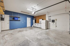 A room with a concrete floor, white cabinets, a blue wall, and a white door. - Luxury Home w Hot Tub Near DFW Airport (Flower Mound)