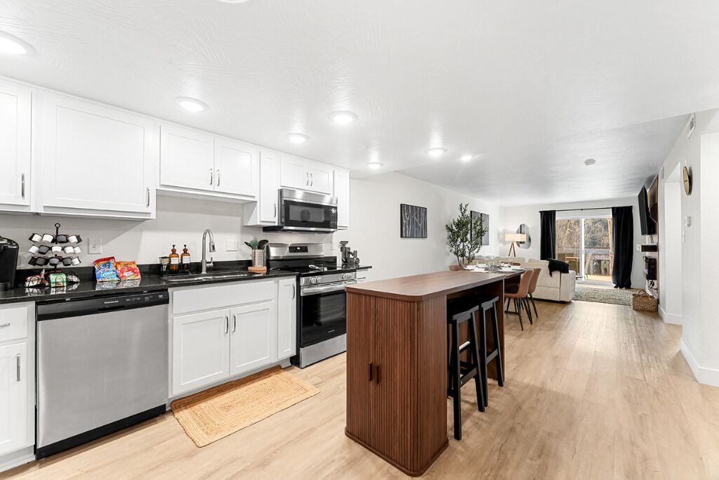 A modern kitchen with white cabinets, stainless steel appliances, and a wooden island.