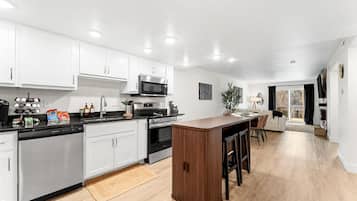 A modern kitchen with white cabinets, stainless steel appliances, and a wooden island.