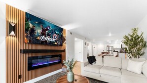Uma sala de estar moderna com televisão de tela plana, lareira, sofá e área de refeições.