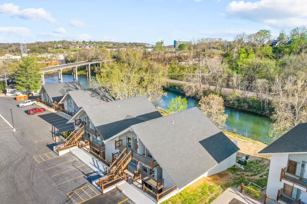 A hotel with a parking lot, a river, and a bridge in the background.
