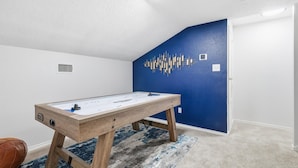 Ein Zimmer mit einem Kicker, einer blauen Akzentwand und einer weißen Decke.