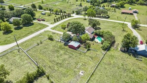 An aerial view of a residential area with houses, a swimming pool, and a fenced yard. - 3BD Farmhouse Country Living - Pool, Patio, Firepit (McKinney)