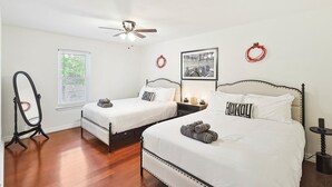 A hotel room with two beds, a ceiling fan, a standing mirror, a framed picture, and a small table with a lamp. - 3BD Farmhouse Country Living - Pool, Patio, Firepit (McKinney)