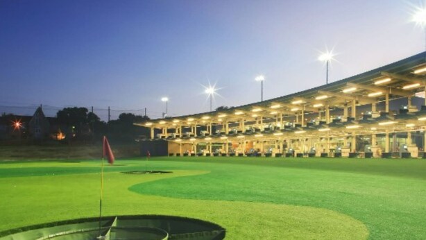 A golf course at dusk with a well-lit clubhouse and a flag on the green. - 3BD Farmhouse Country Living - Pool, Patio, Firepit (McKinney)