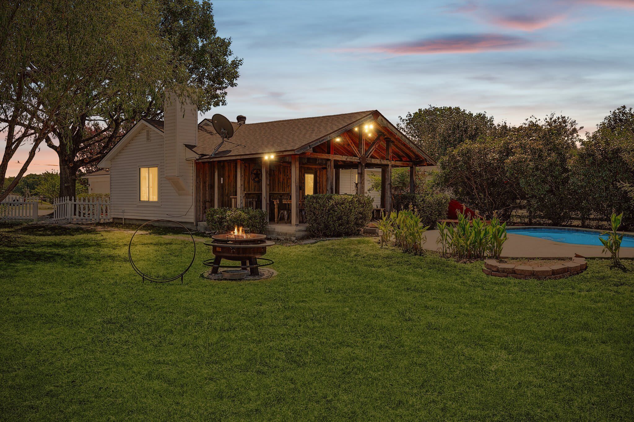 A house with a covered porch, a fire pit, and a swimming pool.