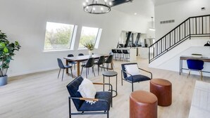 Un salón espacioso con una mesa de comedor, sillas, una escalera y una cocina al fondo.