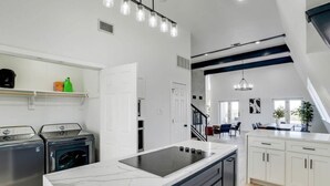 Una cocina moderna con una isla central, electrodomésticos integrados y un comedor con una escalera.