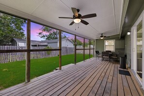 A covered deck with a ceiling fan, outdoor seating, and a view of a backyard with a wooden fence. - Inactive (Sherman)