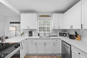 A modern kitchen with white cabinets, a built-in microwave, a sink, and a coffee maker. - Inactive (Sherman)