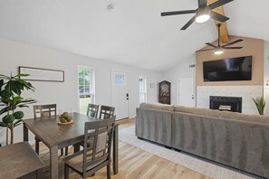 A modern living room with a dining area, a fireplace, and a ceiling fan. - Inactive (Sherman)