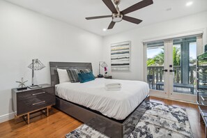 A modern bedroom with a bed, bedside table, lamp, and a view of the balcony. - Tropical Pool Paradise x 6-bd, 4-ba Luxury Living (Miami Lakes)