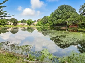 A calm lake with reflections of trees and houses, surrounded by greenery and a wooden fence. - Best of Garland Pool, Cinema Rm, BBQ (Garland)