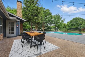 A patio with a table and chairs, a pool, and a brick building with a chimney. - Best of Garland Pool, Cinema Rm, BBQ (Garland)